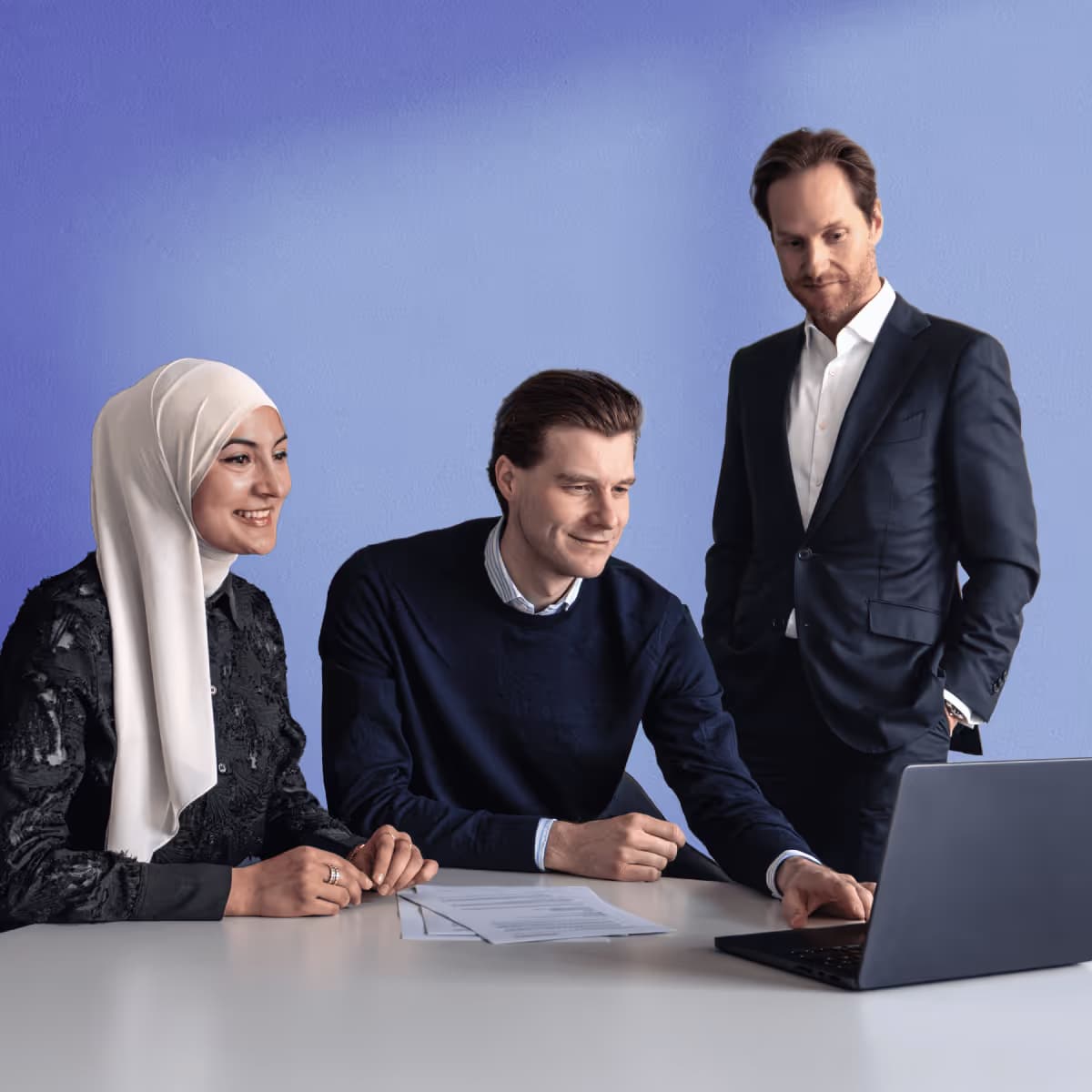 Three businesspeople working together on a laptop in an office