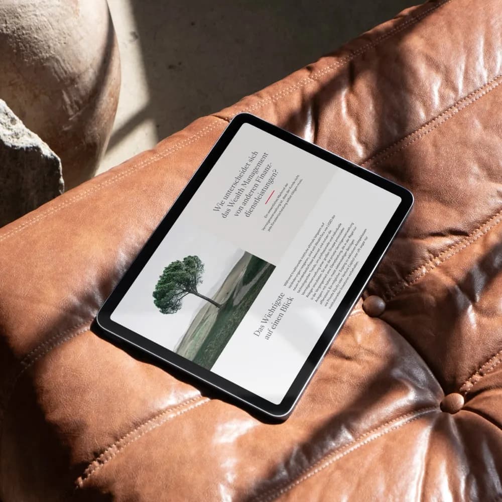 Tablet with a text page and a tree, lying on a brown leather sofa