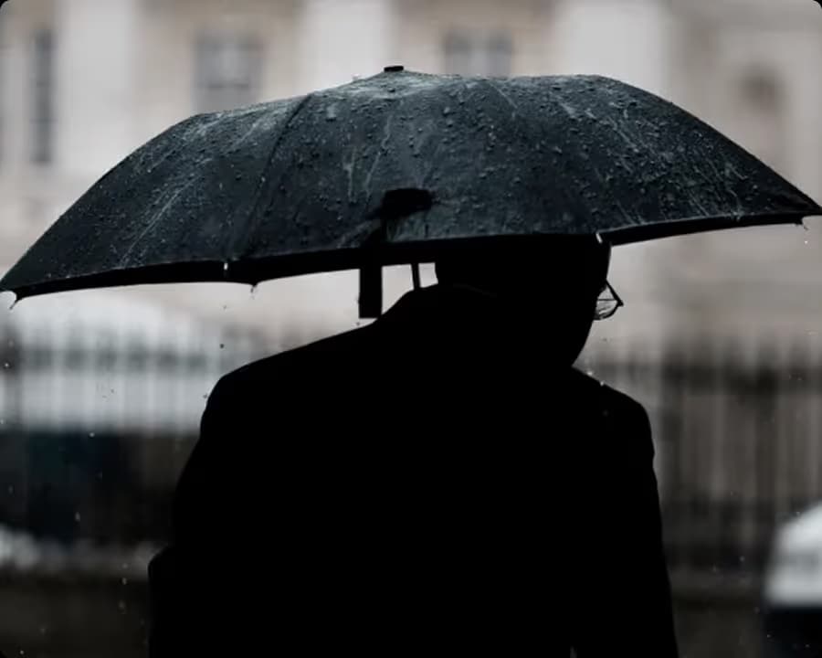 Black silhouette with an umbrella on a rainy, overcast day