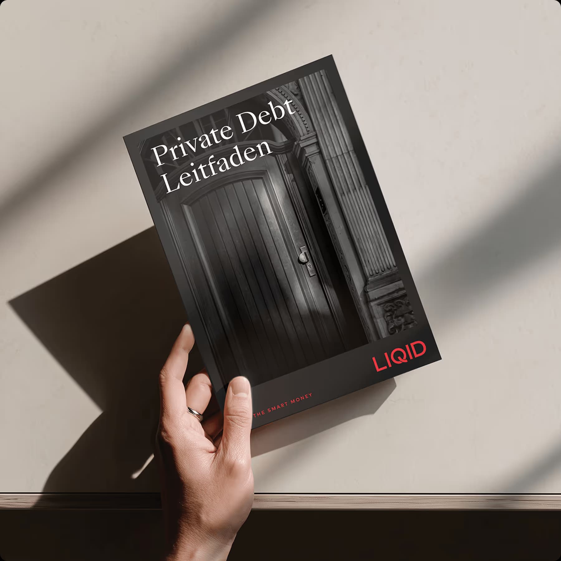 Hand holding the ZUWAX ‘Private Debt Guide’ book against a grey background